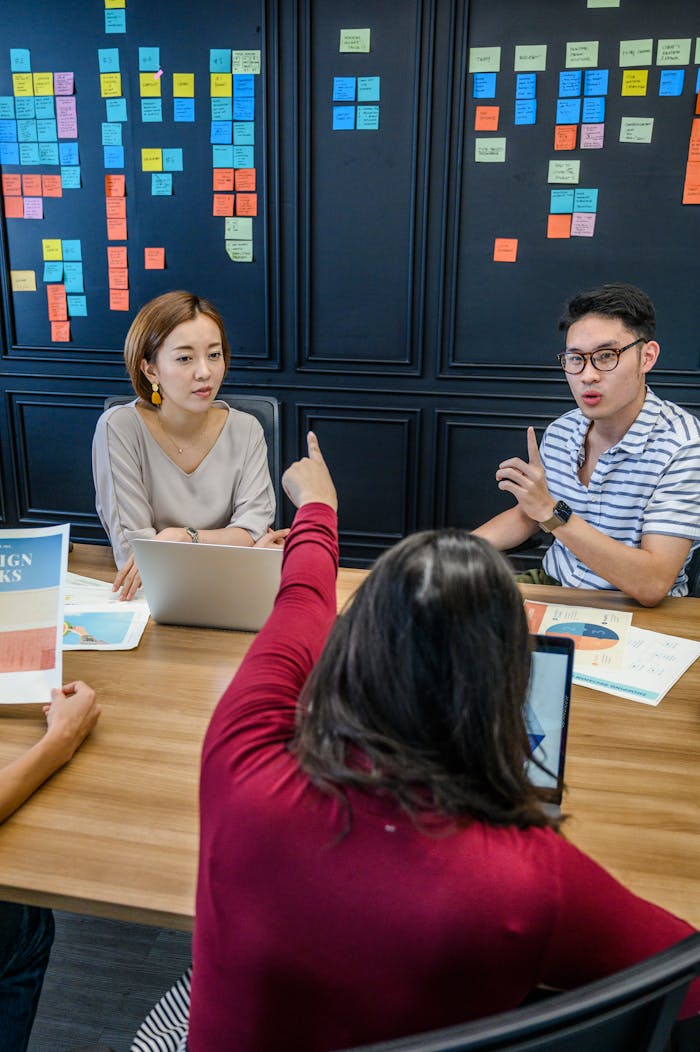 A team engaged in a collaborative meeting with laptops and colorful sticky notes on a wall.